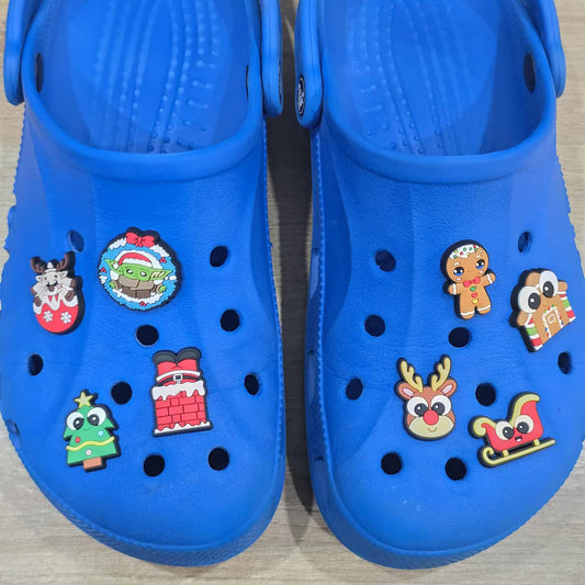 Blue clogs with various colorful Christmas-themed buttons on a wooden surface