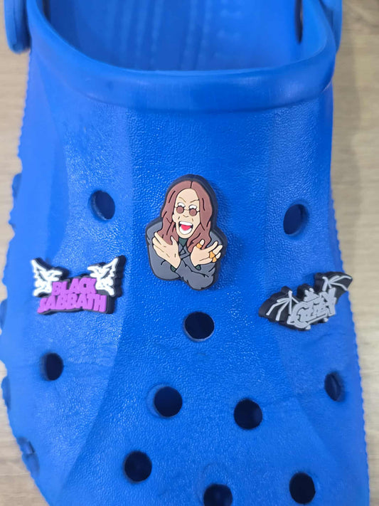 Blue clog with Black Sabbath-themed pins on a wooden surface