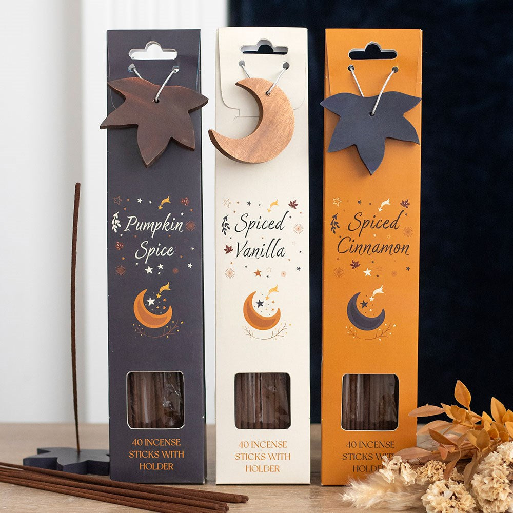 Three packages of incense sticks with holder labeled 'Pumpkin Spice', 'Spiced Vanilla', and 'Spiced Cinnamon' on a dark background.