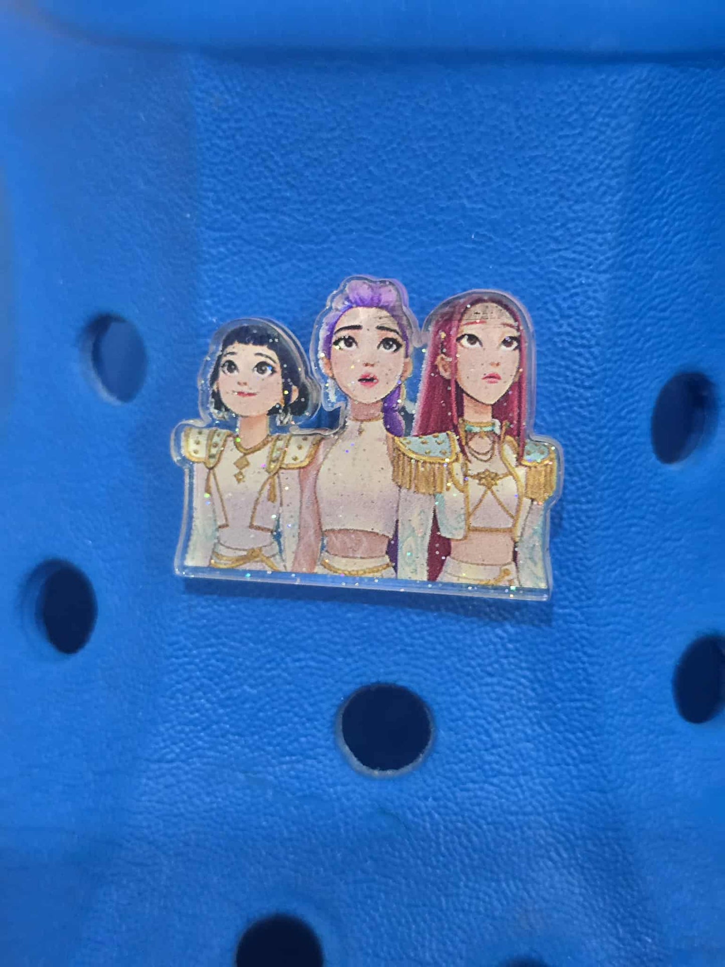 Blue croc shoe with a clear vinyl sticker featuring three animated characters on a blue background