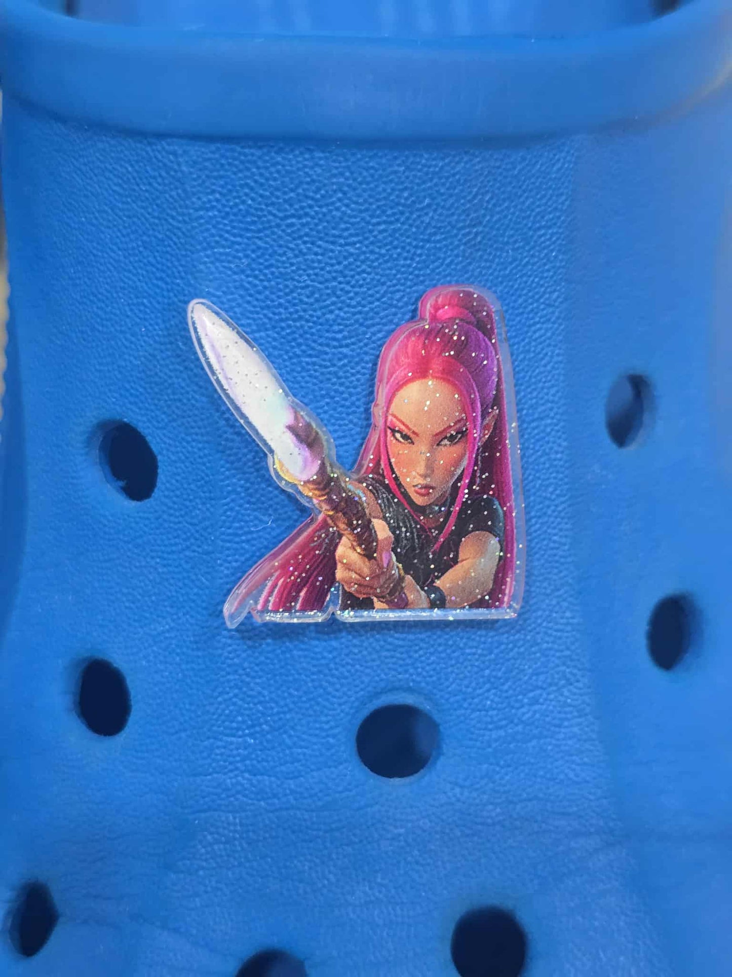 Blue croc shoe with a character wearing pink hair and holding a sword on a clear background