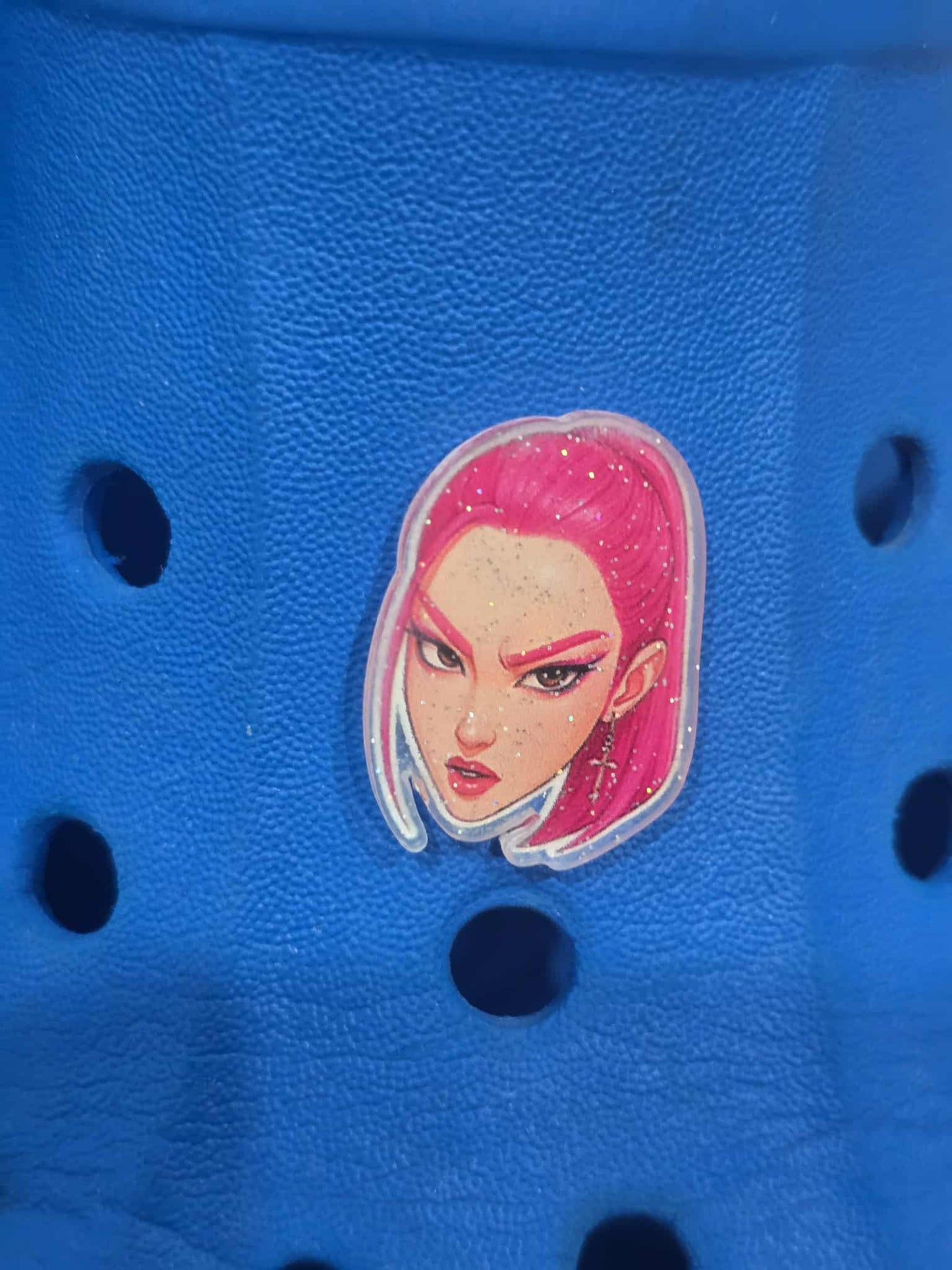 Blue croc shoe with a colorful character sticker on a blue background