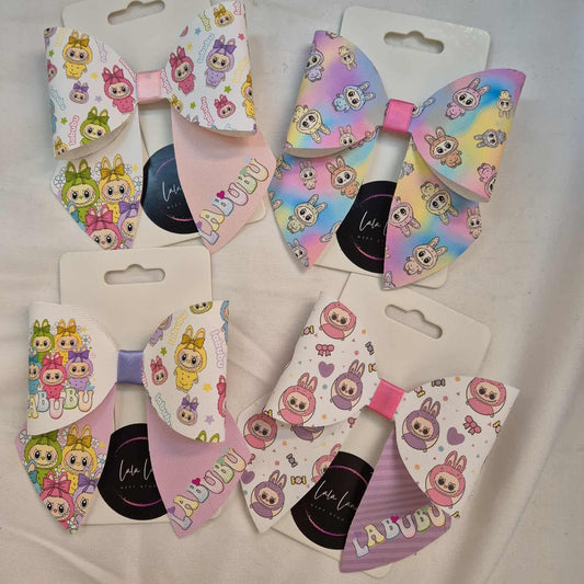 Set of colorful hair bows with cartoon character design on white packaging