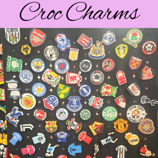 Croc Charms/Jibbitz hanging on a black hanger. A purple box with black writing saying Croc Charms 